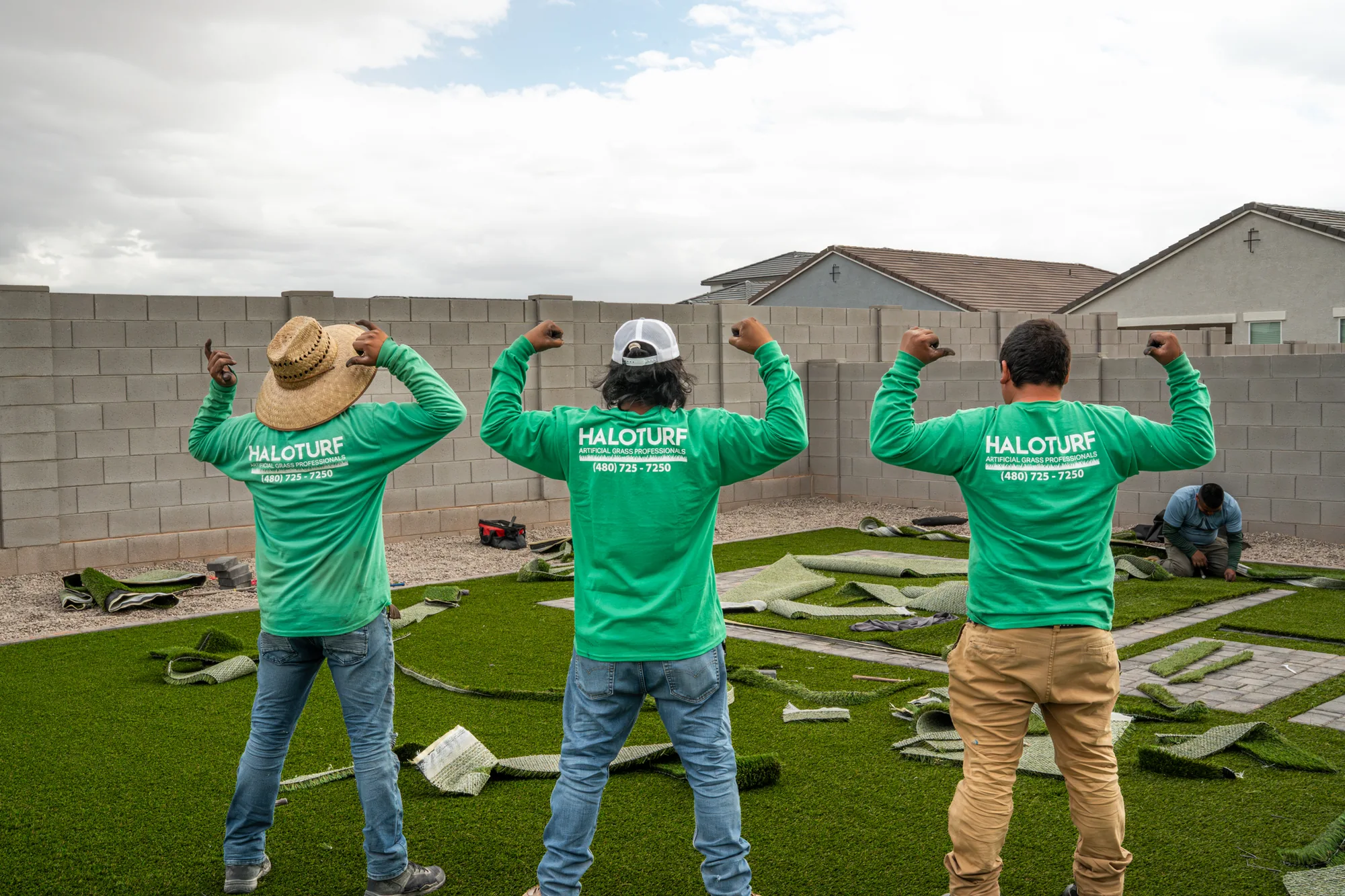 Halo Turf crew in green company shirts beside a backyard turf installation