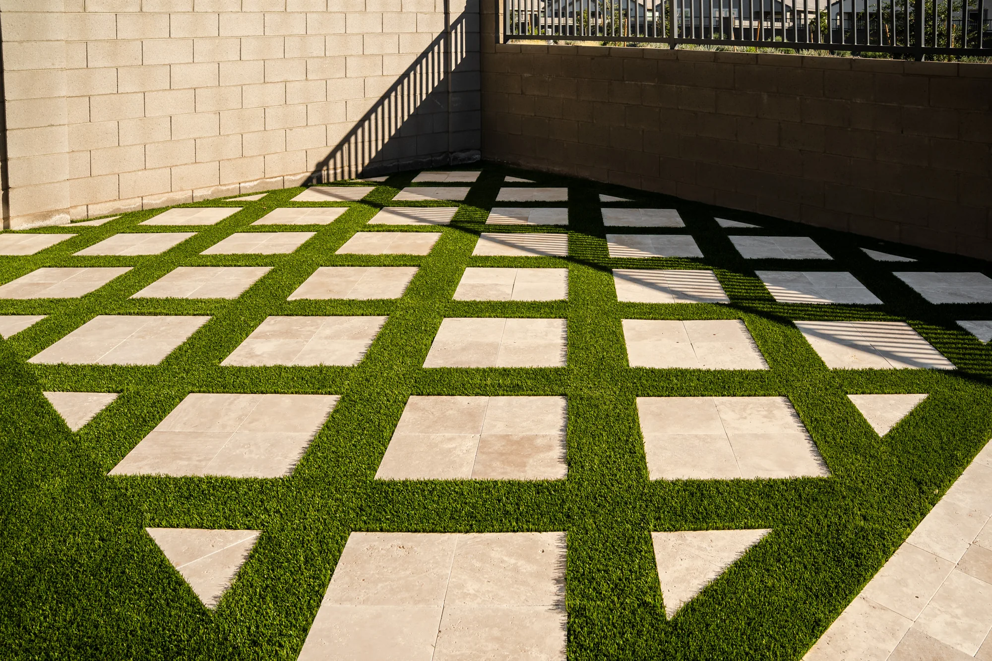 Square stone pavers set in a geometric grid of artificial turf